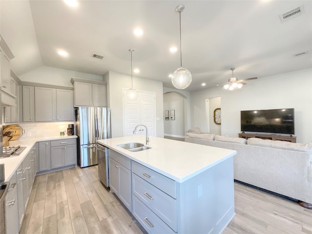 kitchen with hanging light fixtures, sink, gray cabinets, an island with sink, and appliances with stainless steel finishes