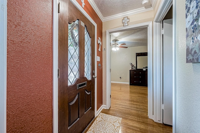 entrance foyer with a textured ceiling, light hardwood / wood-style flooring, and crown molding