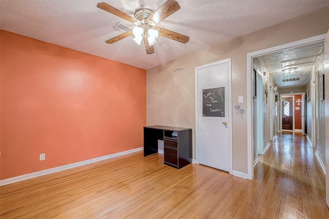 unfurnished office featuring a textured ceiling, light hardwood / wood-style flooring, and ceiling fan