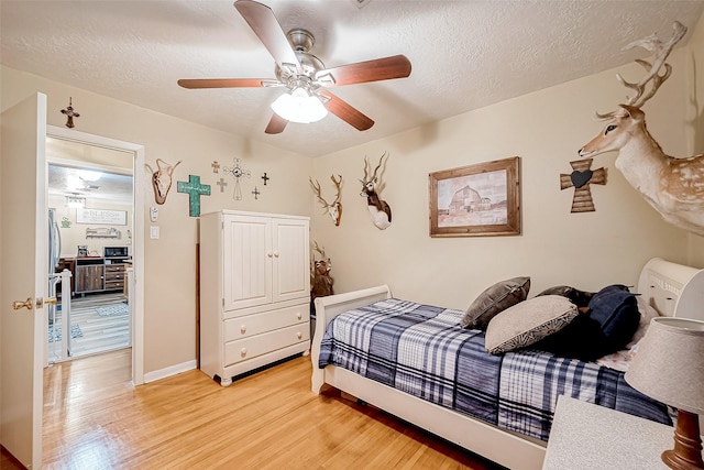 bedroom featuring ceiling fan, light hardwood / wood-style flooring, and a textured ceiling