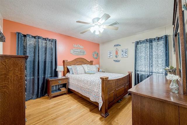 bedroom featuring ceiling fan, a textured ceiling, and light wood-type flooring