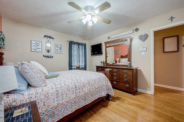 bedroom featuring light wood-type flooring, a textured ceiling, and ceiling fan