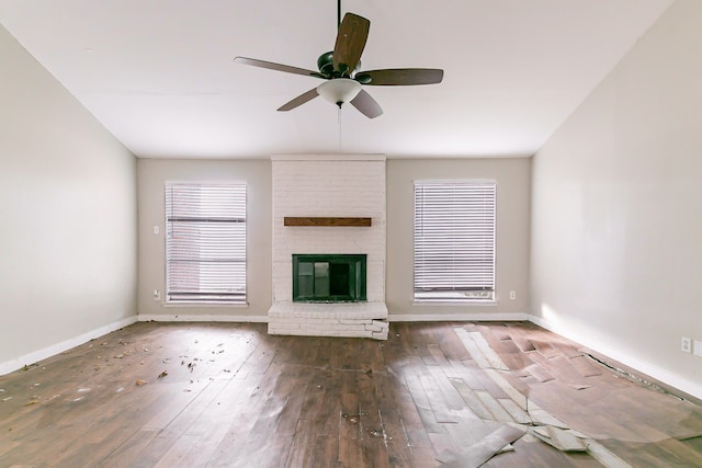 unfurnished living room with ceiling fan, dark wood-type flooring, and a brick fireplace