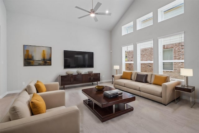 living room with ceiling fan, light wood-type flooring, and high vaulted ceiling