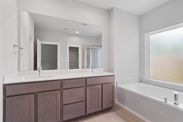 bathroom featuring vanity and independent shower and bath