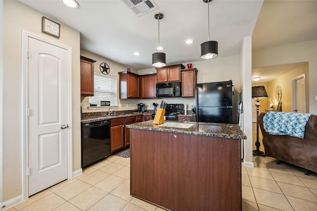 kitchen featuring dark stone countertops, a center island, black appliances, hanging light fixtures, and light tile patterned floors