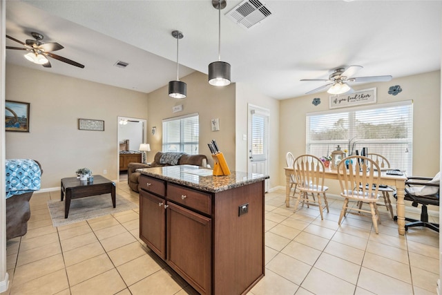 kitchen with decorative light fixtures, plenty of natural light, light tile patterned floors, and dark stone counters