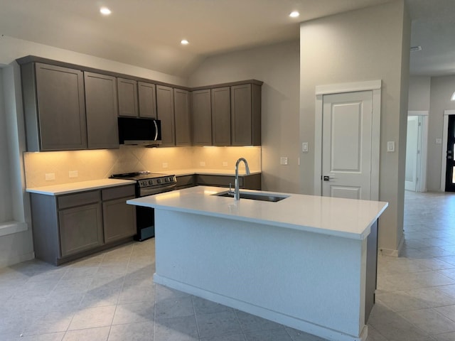 kitchen with stainless steel appliances, a sink, light countertops, tasteful backsplash, and a center island with sink