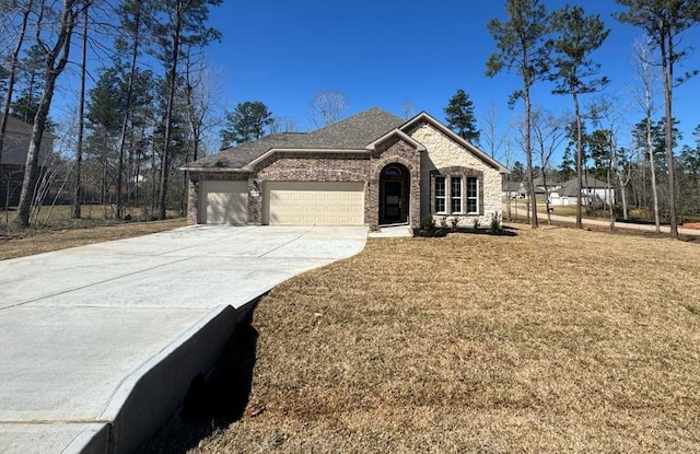 french country style house with an attached garage, a front lawn, concrete driveway, and brick siding