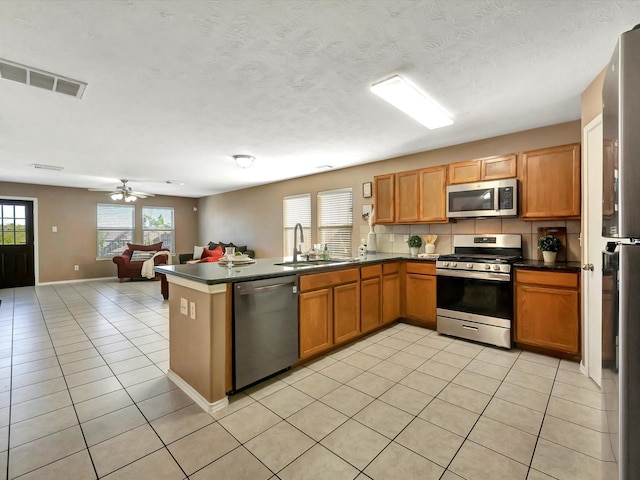 kitchen featuring sink, tasteful backsplash, light tile patterned flooring, kitchen peninsula, and stainless steel appliances