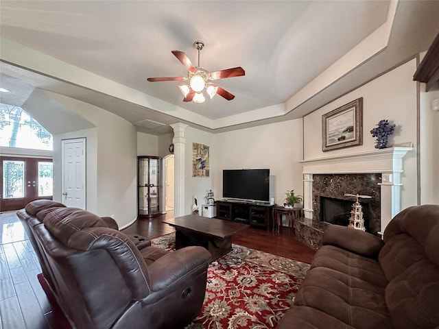 living room with dark hardwood / wood-style floors, ceiling fan, a raised ceiling, and a fireplace