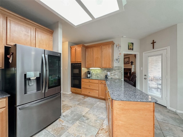 kitchen featuring decorative backsplash, stainless steel refrigerator with ice dispenser, kitchen peninsula, dark stone counters, and black double oven