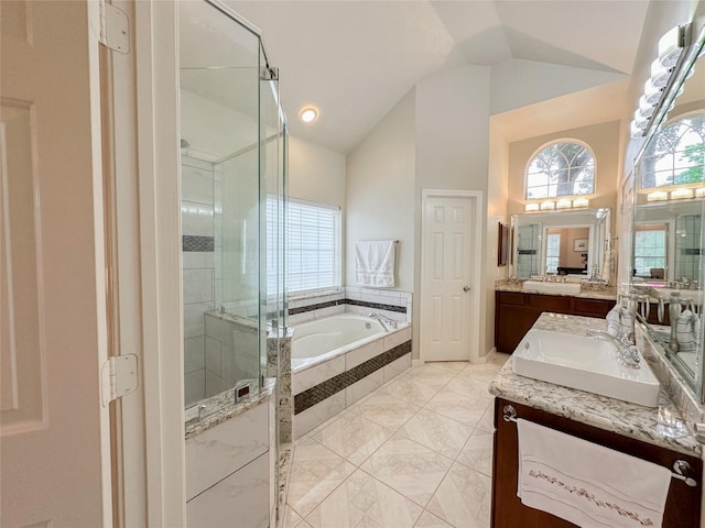 bathroom with plus walk in shower, vanity, vaulted ceiling, and a wealth of natural light