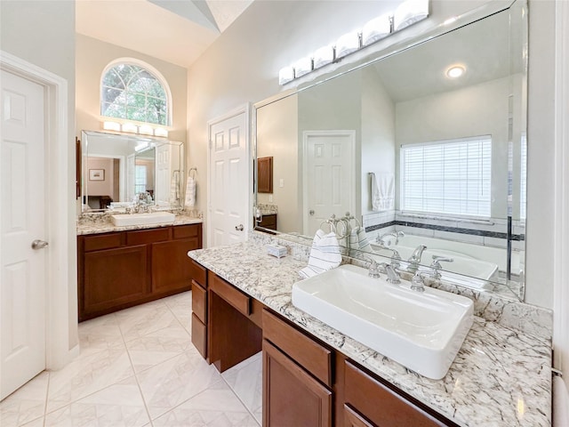 bathroom with a washtub, vanity, and lofted ceiling