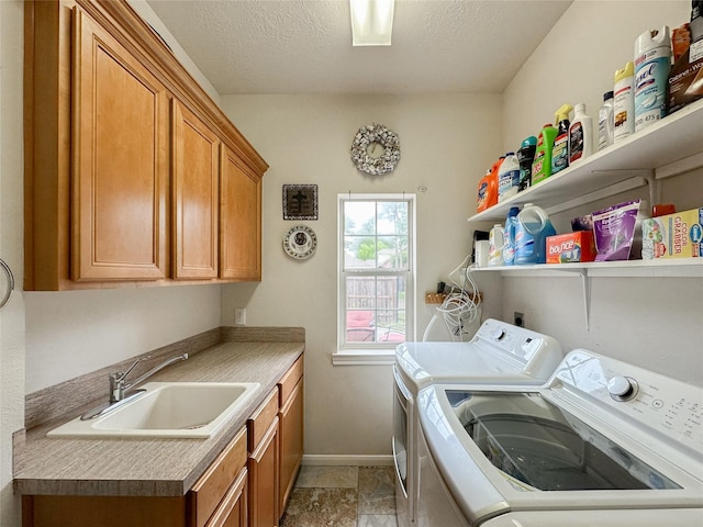 washroom featuring a textured ceiling, cabinets, sink, and washing machine and clothes dryer