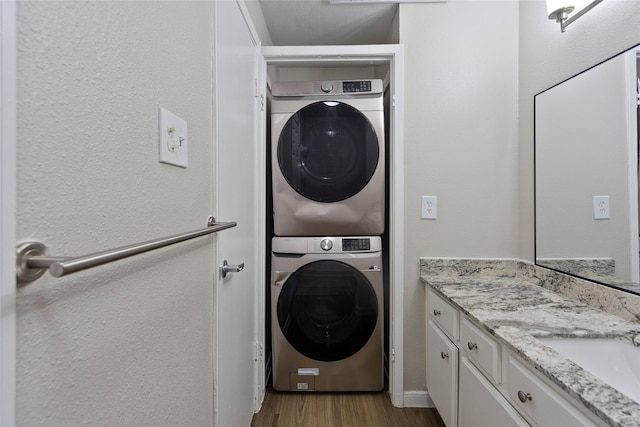 washroom featuring light hardwood / wood-style floors, sink, and stacked washer and clothes dryer