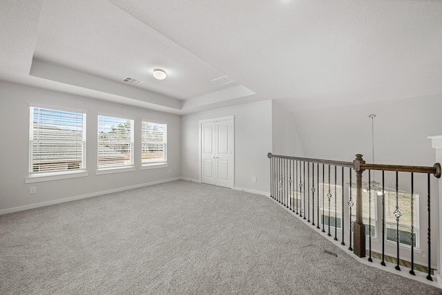 unfurnished room featuring a raised ceiling and carpet floors