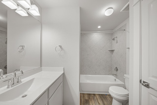 full bathroom featuring toilet, vanity, hardwood / wood-style floors, and tiled shower / bath combo