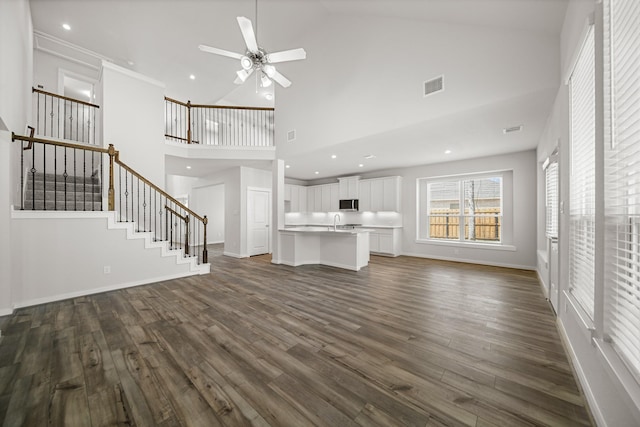 unfurnished living room featuring ceiling fan, dark hardwood / wood-style floors, and a towering ceiling