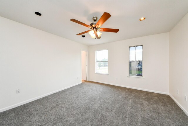 empty room with dark colored carpet and ceiling fan