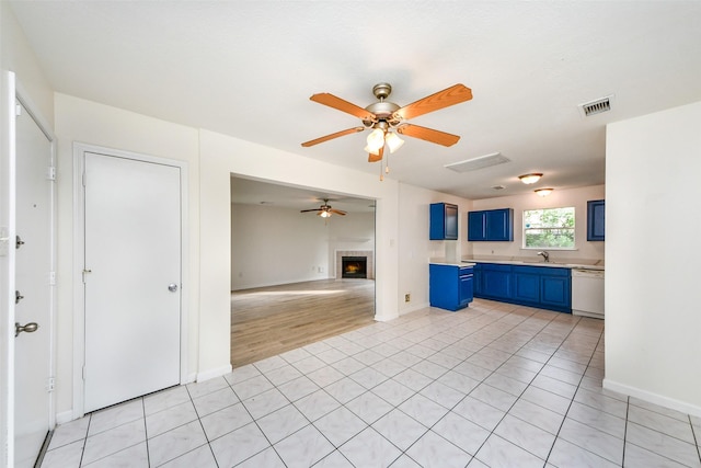 kitchen featuring dishwasher, sink, blue cabinets, and light tile patterned flooring