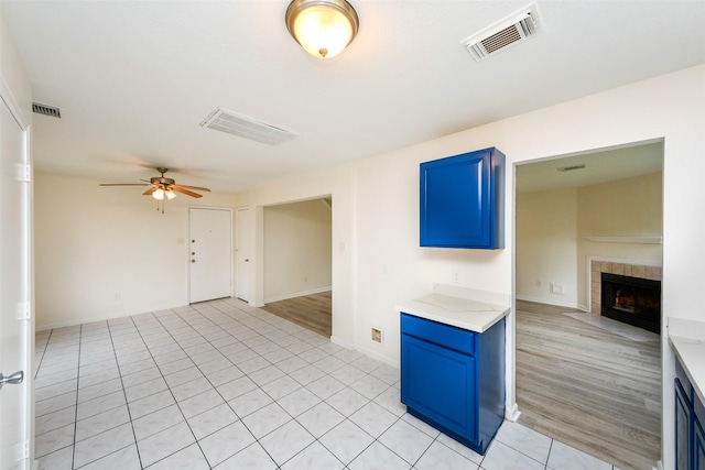 unfurnished living room featuring a tile fireplace, light tile patterned floors, and ceiling fan