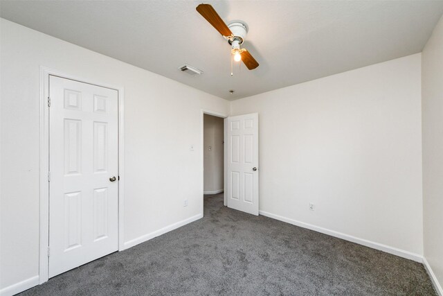 unfurnished bedroom with ceiling fan and dark carpet