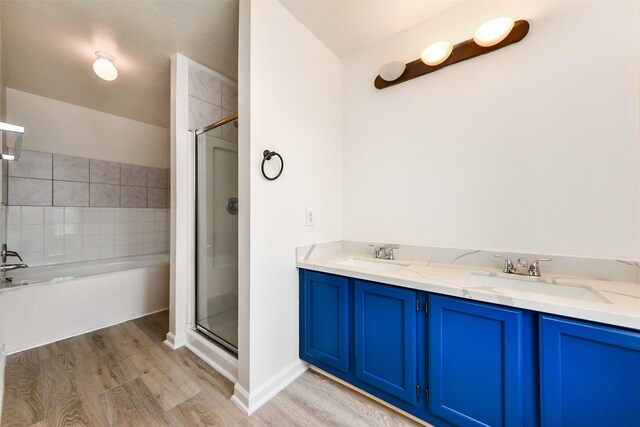 bathroom with wood-type flooring, vanity, and shower with separate bathtub