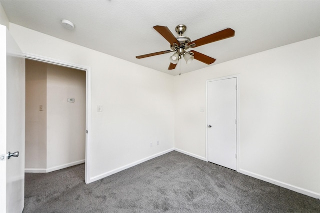 empty room with dark colored carpet and ceiling fan