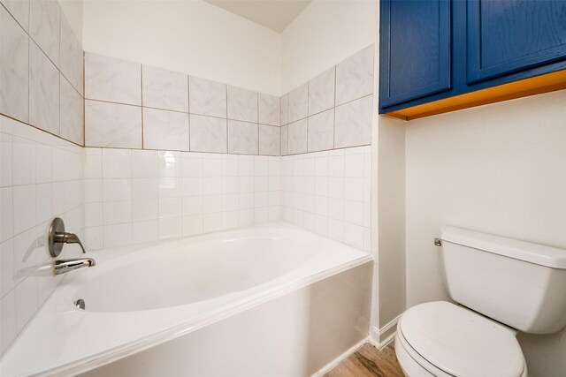 bathroom featuring hardwood / wood-style flooring, toilet, and a bath