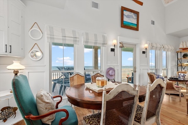 dining room featuring a high ceiling, light hardwood / wood-style flooring, and a healthy amount of sunlight