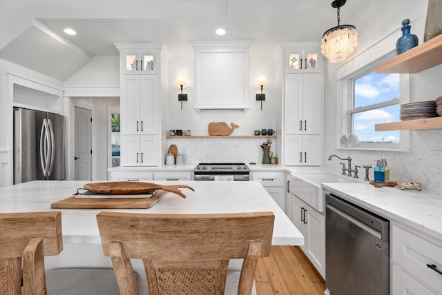 kitchen with sink, white cabinets, hanging light fixtures, and appliances with stainless steel finishes