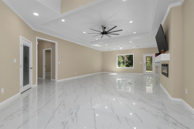 unfurnished living room with a tray ceiling, ceiling fan, and crown molding