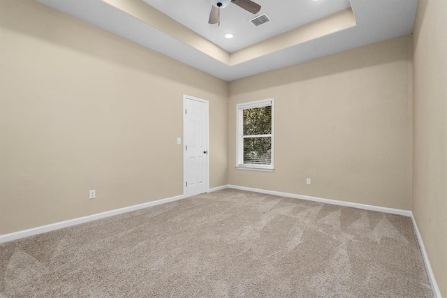 unfurnished room featuring a raised ceiling, ceiling fan, and carpet flooring