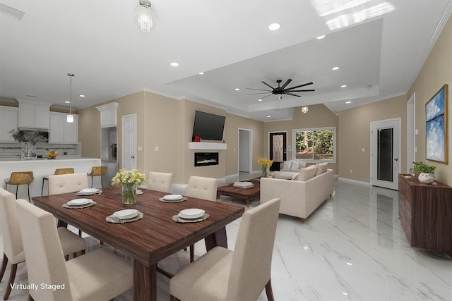 dining room featuring a raised ceiling, ceiling fan, and ornamental molding