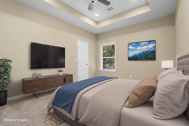 carpeted bedroom with a tray ceiling and ceiling fan