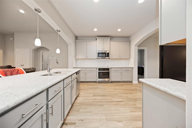 kitchen with tasteful backsplash, hanging light fixtures, sink, stainless steel appliances, and gray cabinets