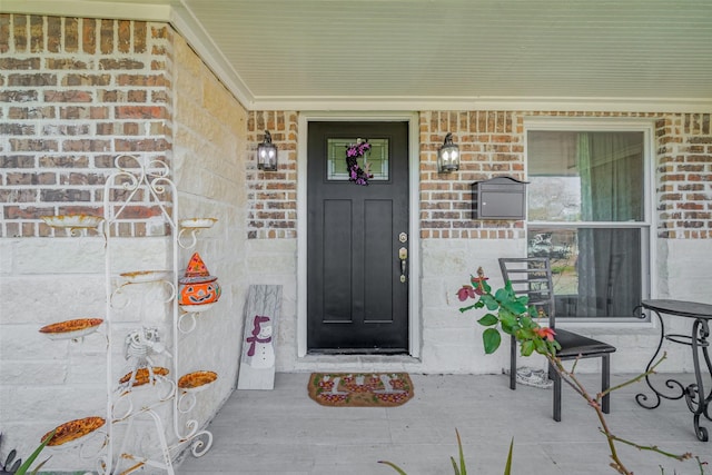 property entrance with covered porch and brick siding