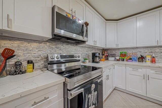 606 S Kaufman Dr, Deer Park, TX 77536 - kitchen with light tile patterned floors, light stone counters, stainless steel appliances, white cabinetry, and backsplash