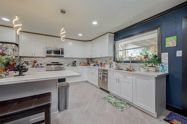 606 S Kaufman Dr, Deer Park, TX 77536 - kitchen featuring hanging light fixtures, a sink, stainless steel appliances, white cabinetry, and backsplash