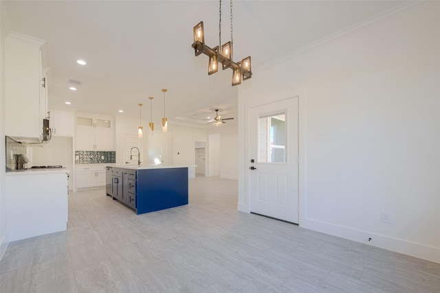 kitchen with blue cabinetry, white cabinetry, tasteful backsplash, an island with sink, and decorative light fixtures