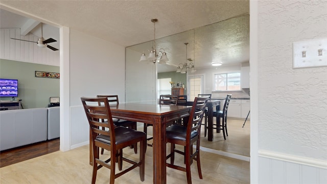 dining space with vaulted ceiling with beams, ceiling fan with notable chandelier, and a textured ceiling