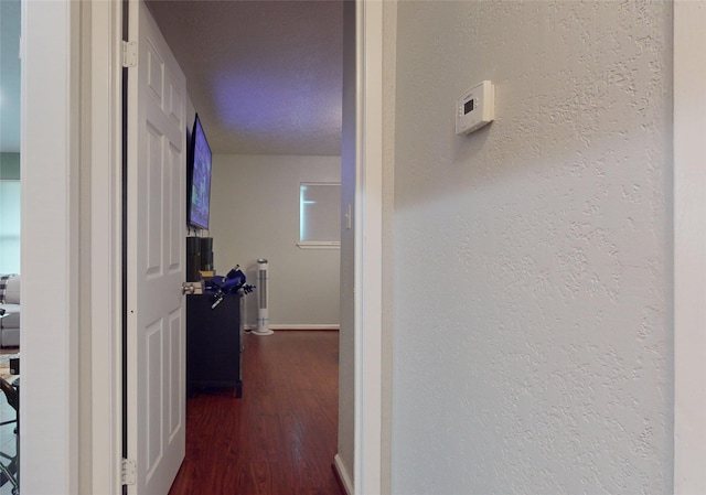 hall featuring a textured ceiling and dark wood-type flooring