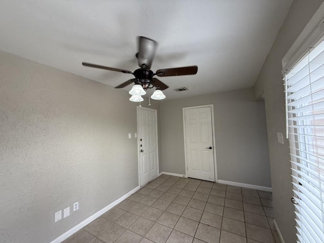 unfurnished room with light tile patterned floors and ceiling fan