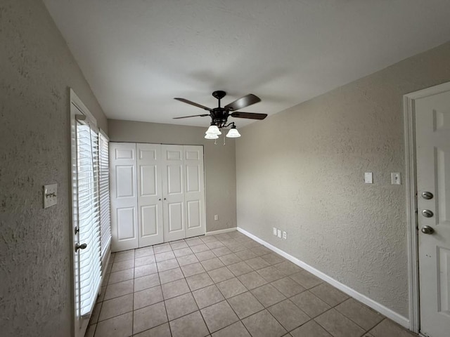 unfurnished bedroom with ceiling fan, a closet, and light tile patterned floors