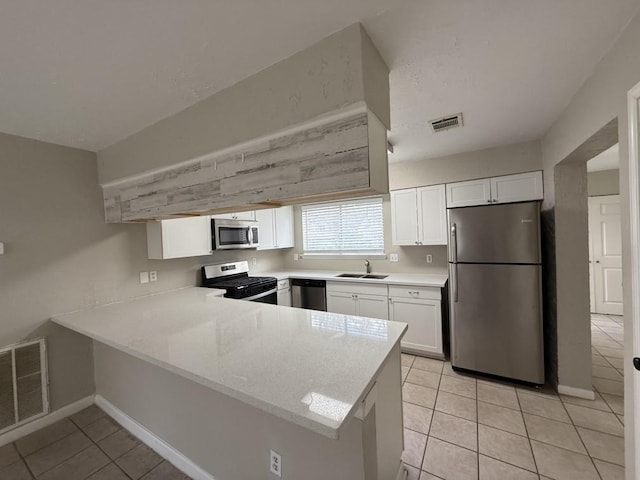 kitchen featuring sink, light tile patterned floors, appliances with stainless steel finishes, white cabinets, and kitchen peninsula