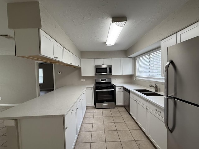 kitchen with stainless steel appliances, kitchen peninsula, sink, and white cabinets