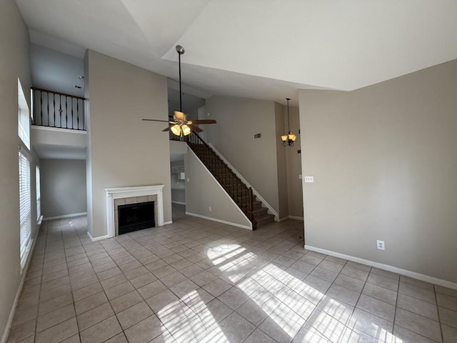 unfurnished living room featuring light tile patterned flooring, ceiling fan, a tiled fireplace, and high vaulted ceiling