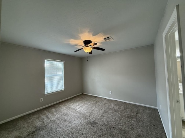 spare room featuring ceiling fan and dark colored carpet