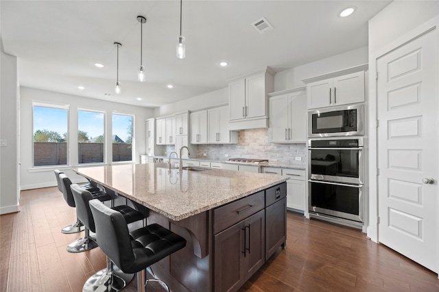 kitchen featuring pendant lighting, sink, an island with sink, white cabinetry, and stainless steel appliances